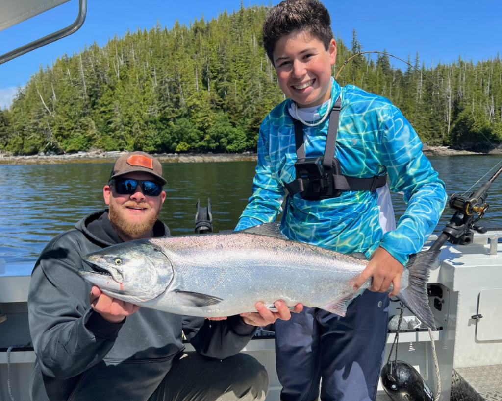 Captain Tony and a guest holding a massive salmon during a ketchikan fishing charter.