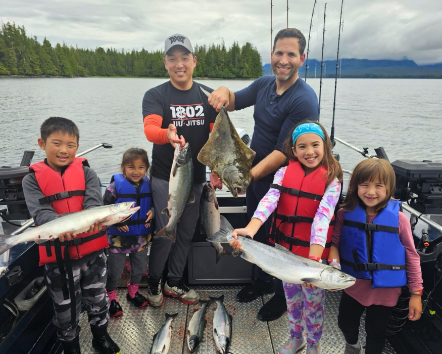 A family on a boat holding salmon and halibut