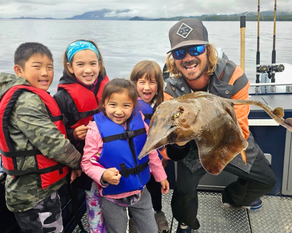 Captain Lukas holding a massive skate fish during a ketchikan fishing charter.