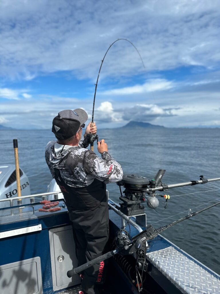 A guy reeling up a fishing rod trying to catch salmon on a sunny day in Ketchikan alaska.