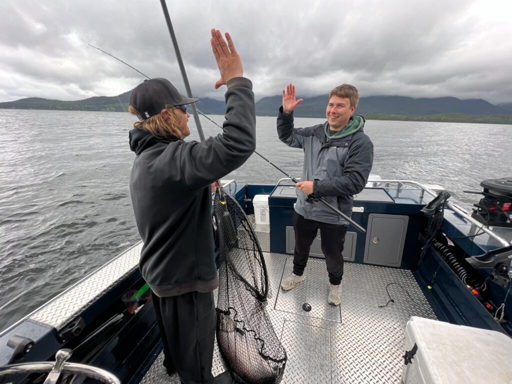 Captain Lukas of Ketchikan Finest Fishing Charters giving a guest a high five after they caught a salmon.
