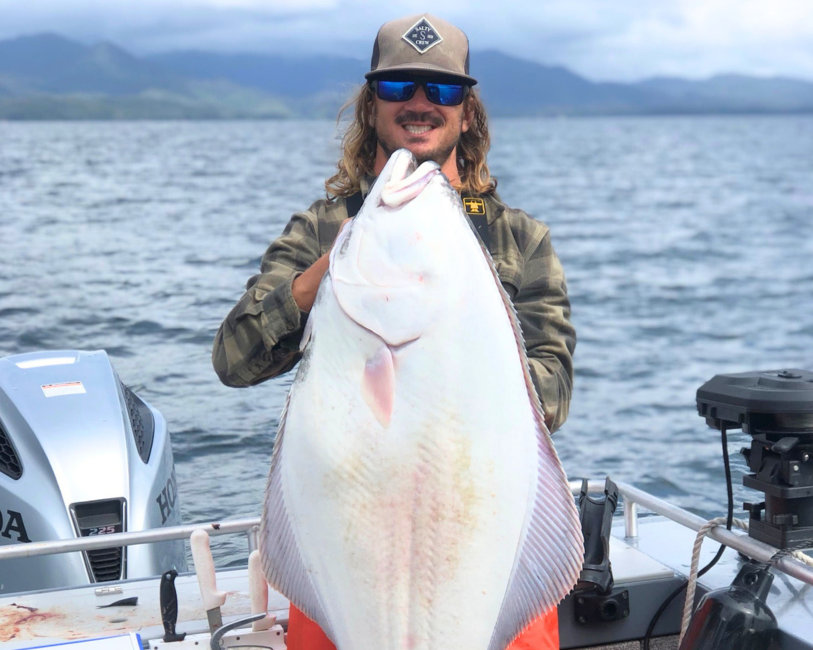 Captain Lukas, a ketchikan fishing guide, holding a massive pacific halibut.
