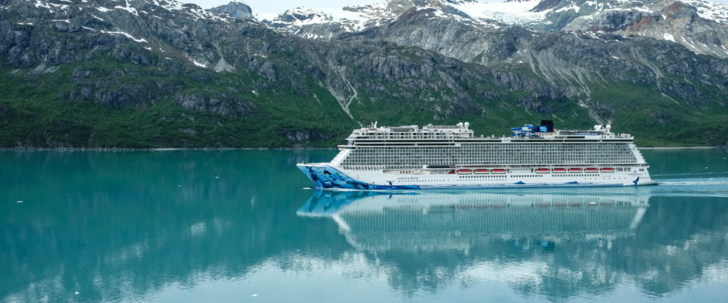 The Norwegian Bliss in the inside passage of southeast alaska with snow capped mountains in the backgroud.